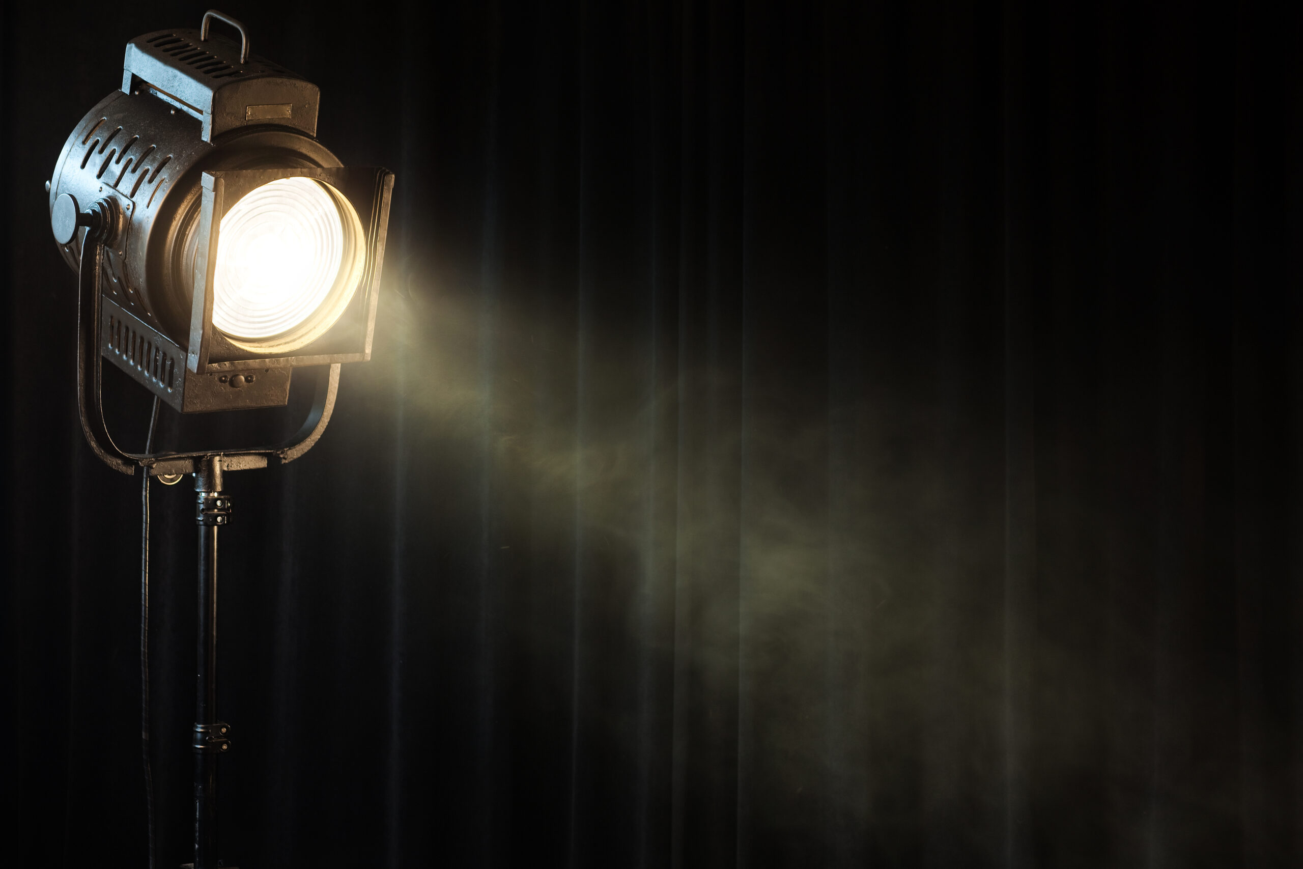 vintage-theatre-spot-light-on-black-curtain-with-wmoke